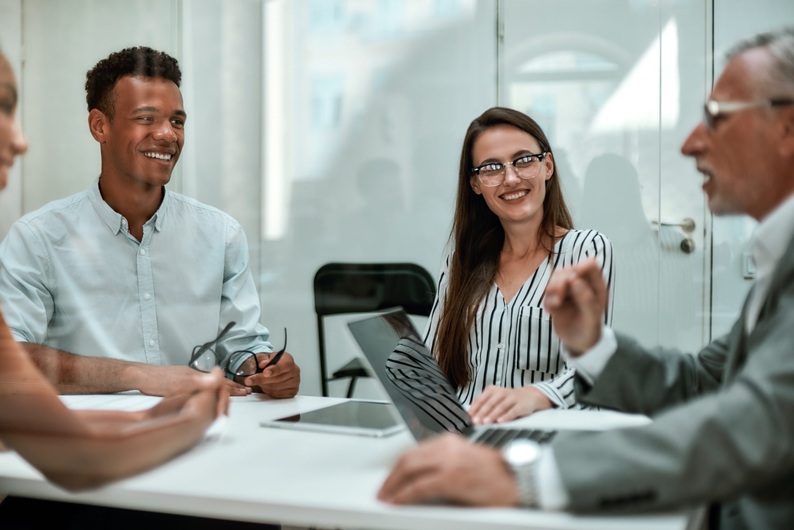 Good day. Young and cheerful coworkers smiling while having a meeting in the modern office. Business concept